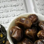 Kurma dan Al-Quran terbuka di atas meja, melambangkan tradisi buka puasa Ramadan